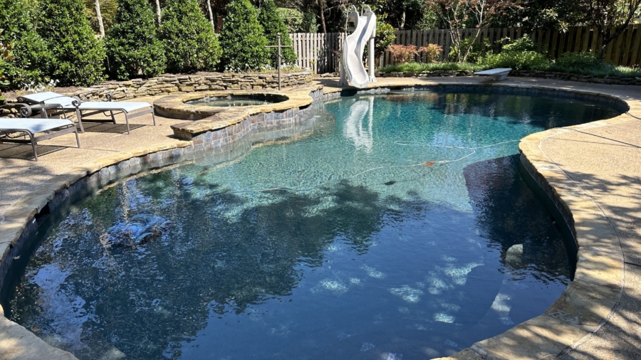 Crystal-clear swimming pool with clean, sparkling water, surrounded by a well-maintained deck, showcasing professional pool cleaning and maintenance services